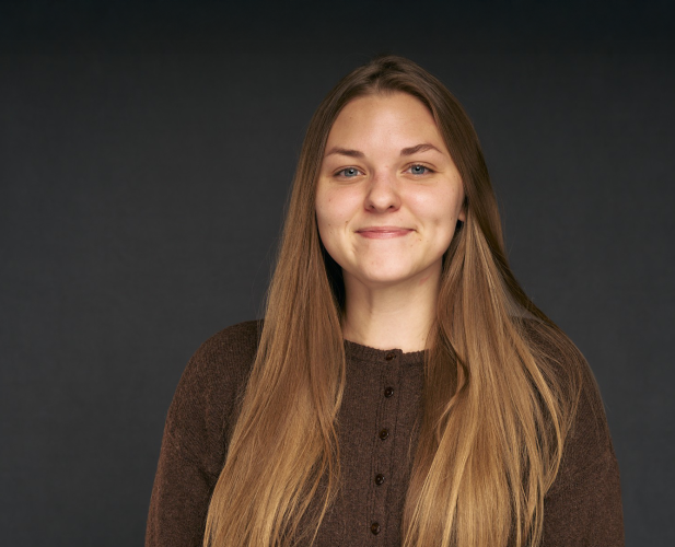 A color photo of a woman smiling for a photo.