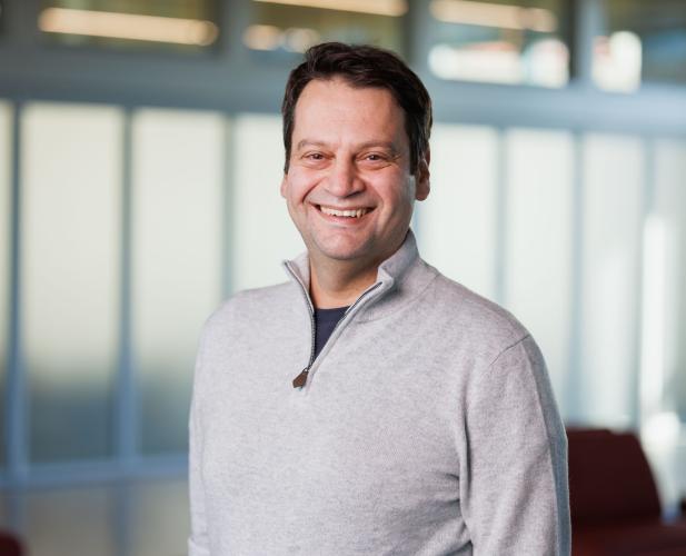 a man with short brown hair wearing a gray sweater