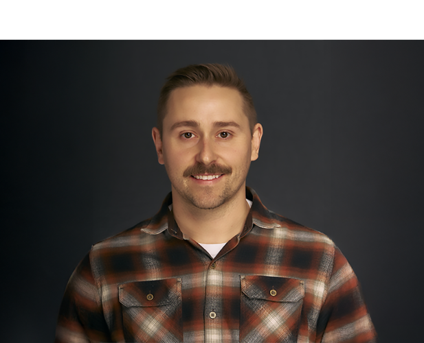 A color photo of a man smiling for a portrait.