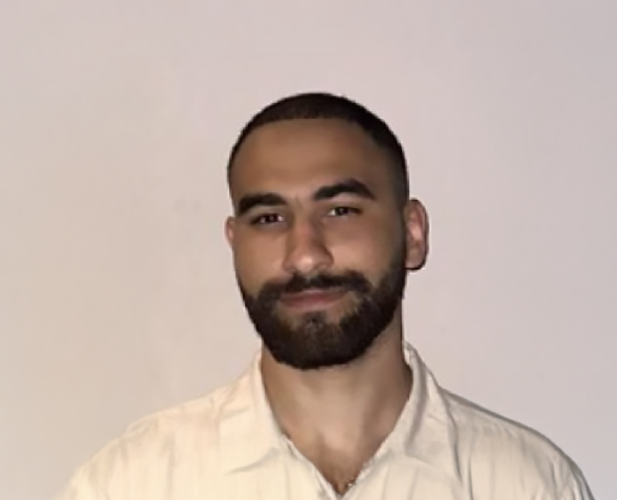 A color photo of a man smiling for a portrait.