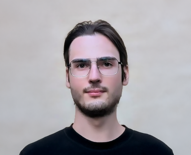 A color photo of a man smiling for a portrait.