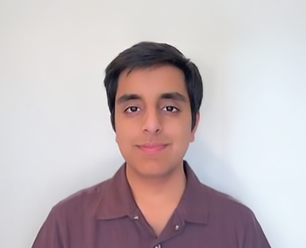 A color photo of a man smiling for a portrait.