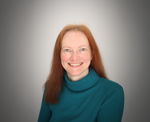 A color photo of a woman smiling for a photo.