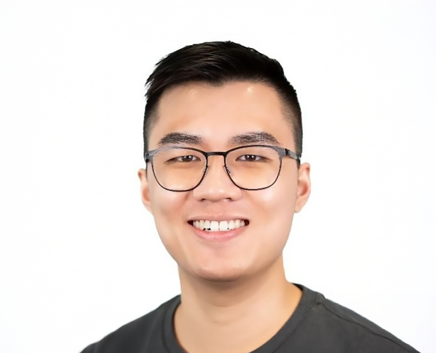 A color photo of a man smiling for a portrait.