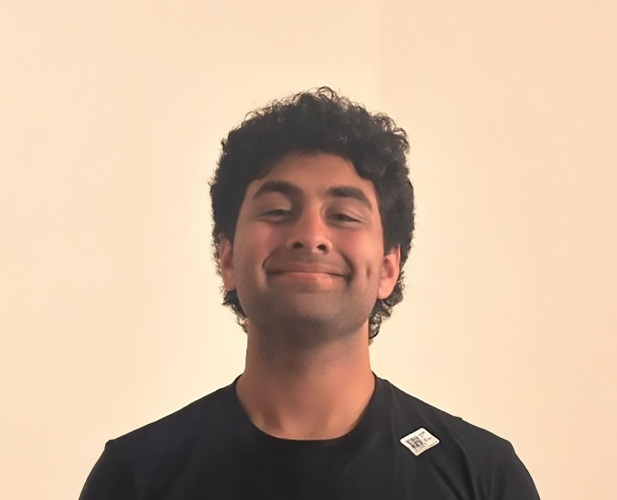 A color photo of a man smiling for a portrait.