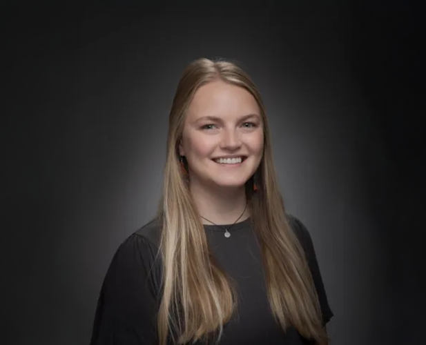 A color photo of a woman smiling for a photo.