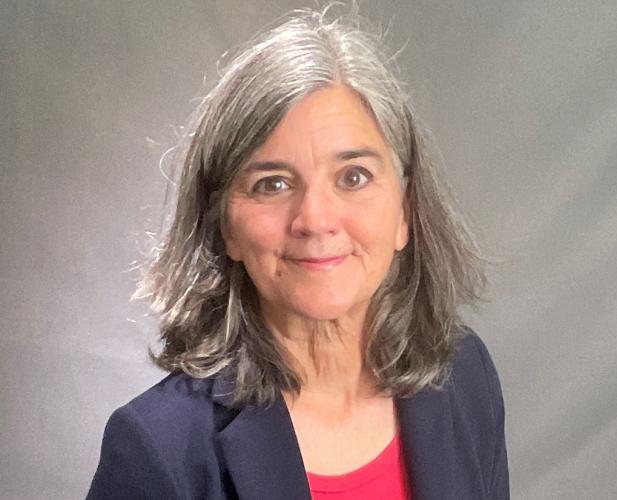 Color portrait of woman with long grey hair in a suit, looking at camera