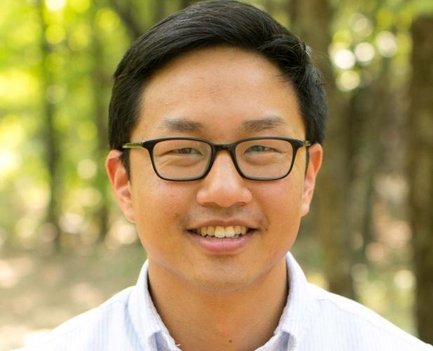 Portrait of a man in white shirt, dark hair and glasses. 