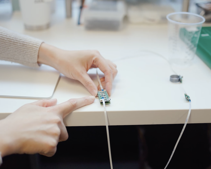 two hands touch a wire and piece of tech