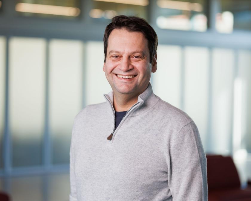 a man with short brown hair wearing a gray sweater