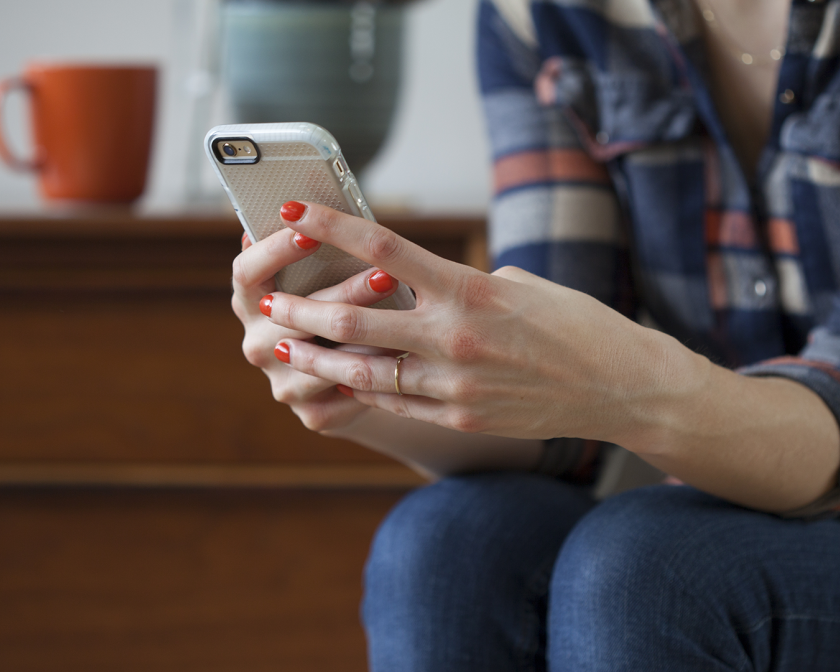 A color photo showing a woman's hands holding a phone. Shutterstock image