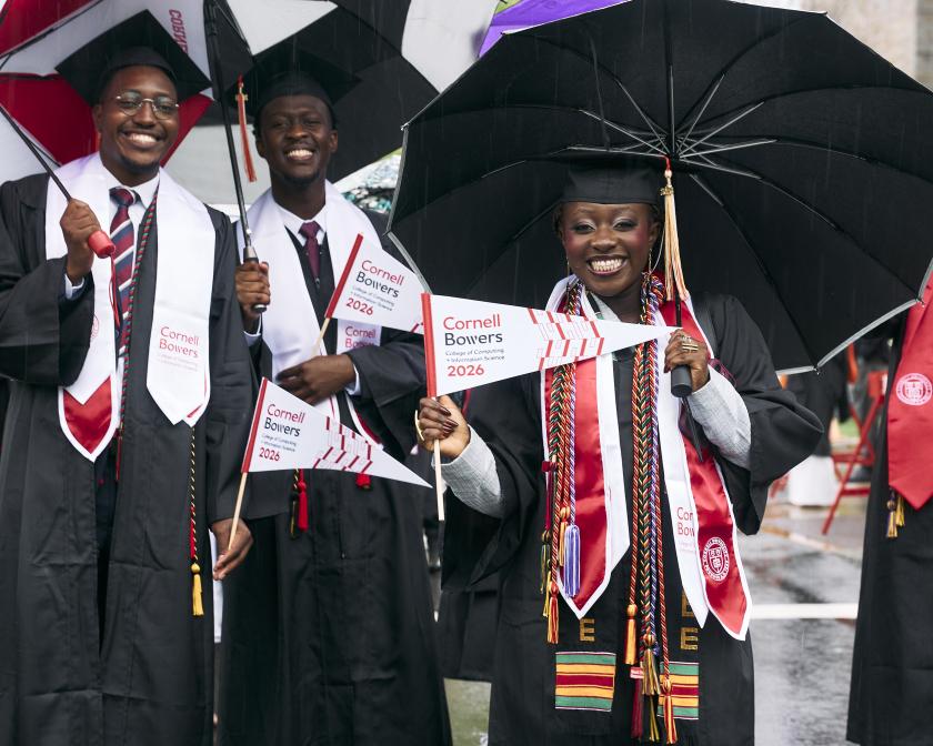 a group of graduates smile under their umbrellas during the procession