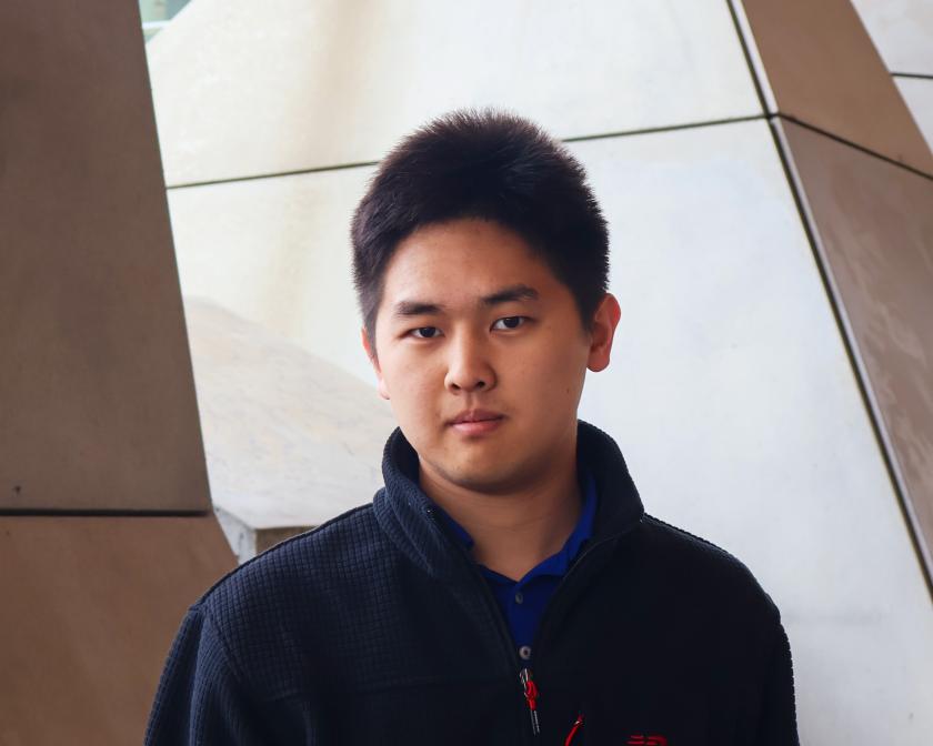 Andrew Kang in front of tan cement pillars
