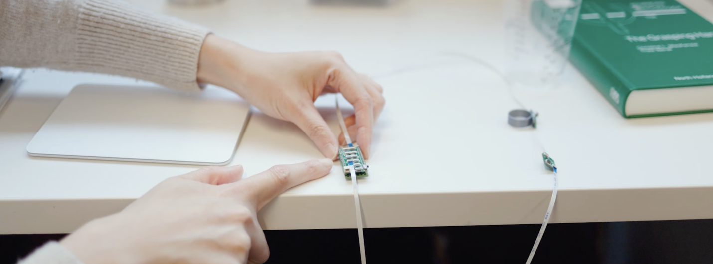 two hands touch a wire and piece of tech