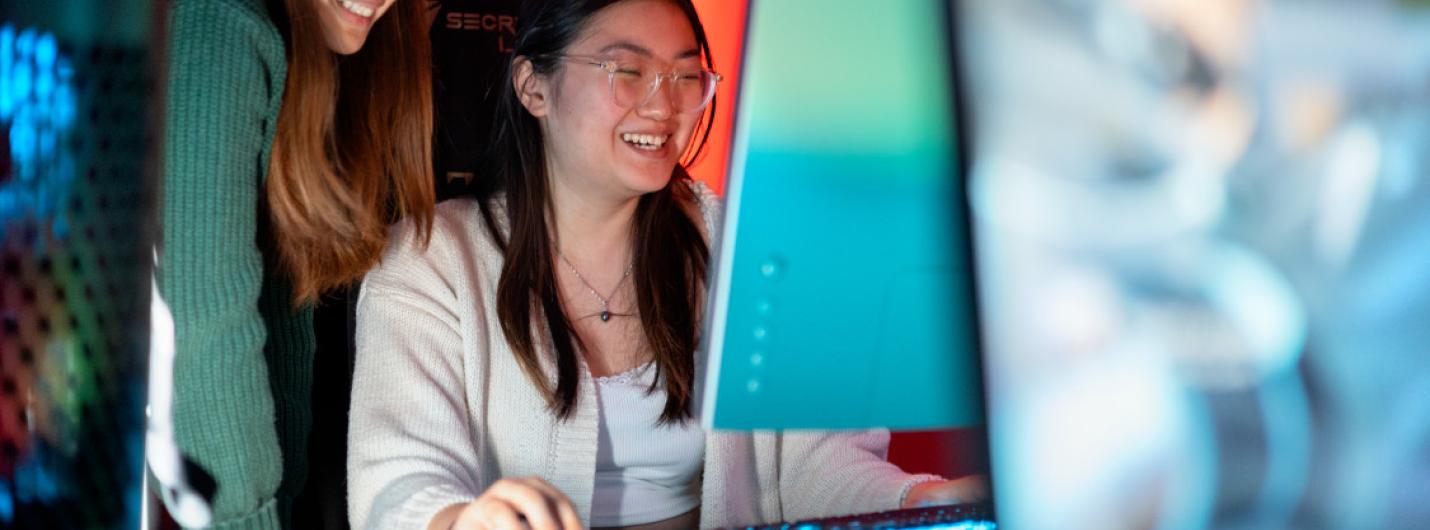 two female students work on a laptop 