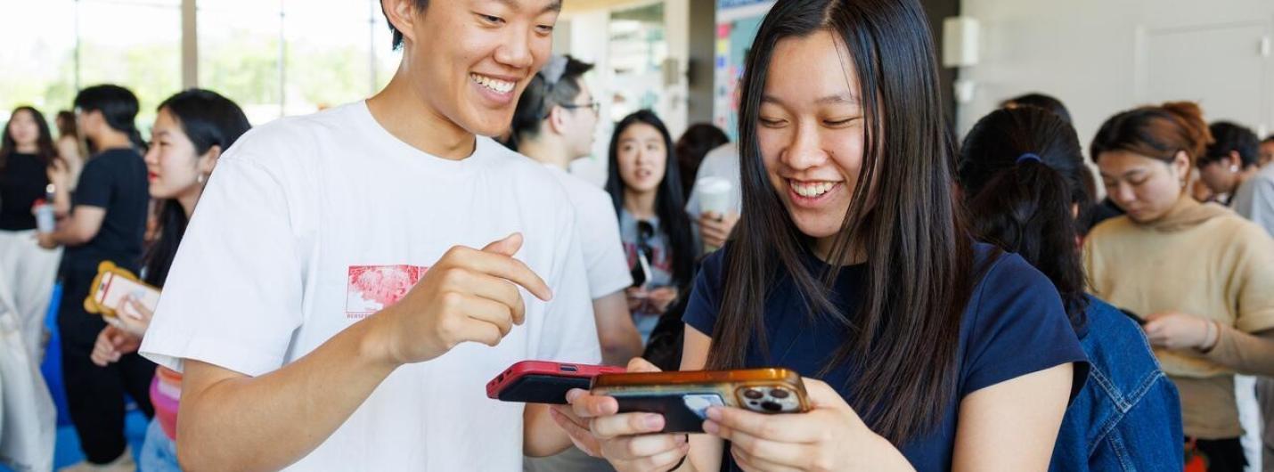 two students play on a handheld device