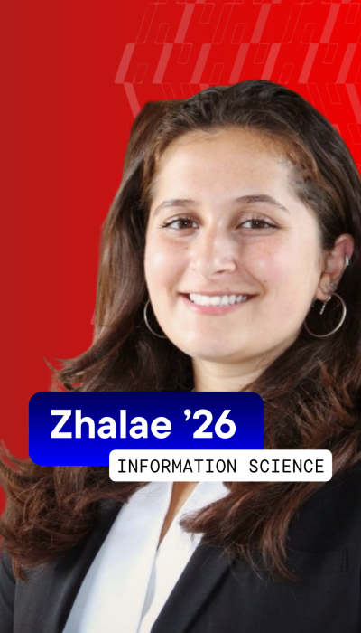 a female student with long wavy brown hair wearing a white button down shirt and black jacket