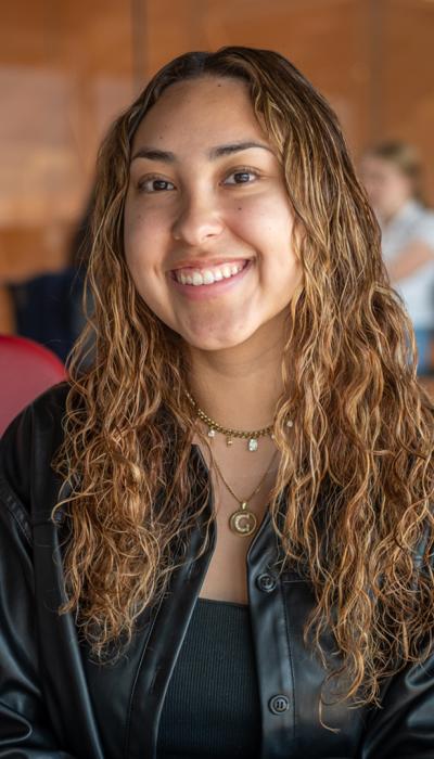 a female latino student sits on a red chair in gates hall