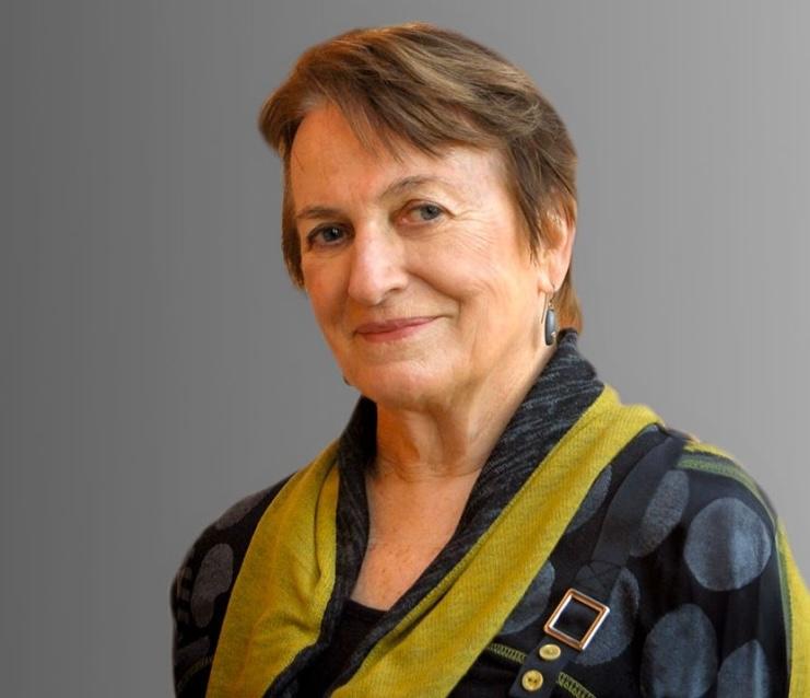 Woman with short hair looking at camera, wearing blue blouse with green scarf