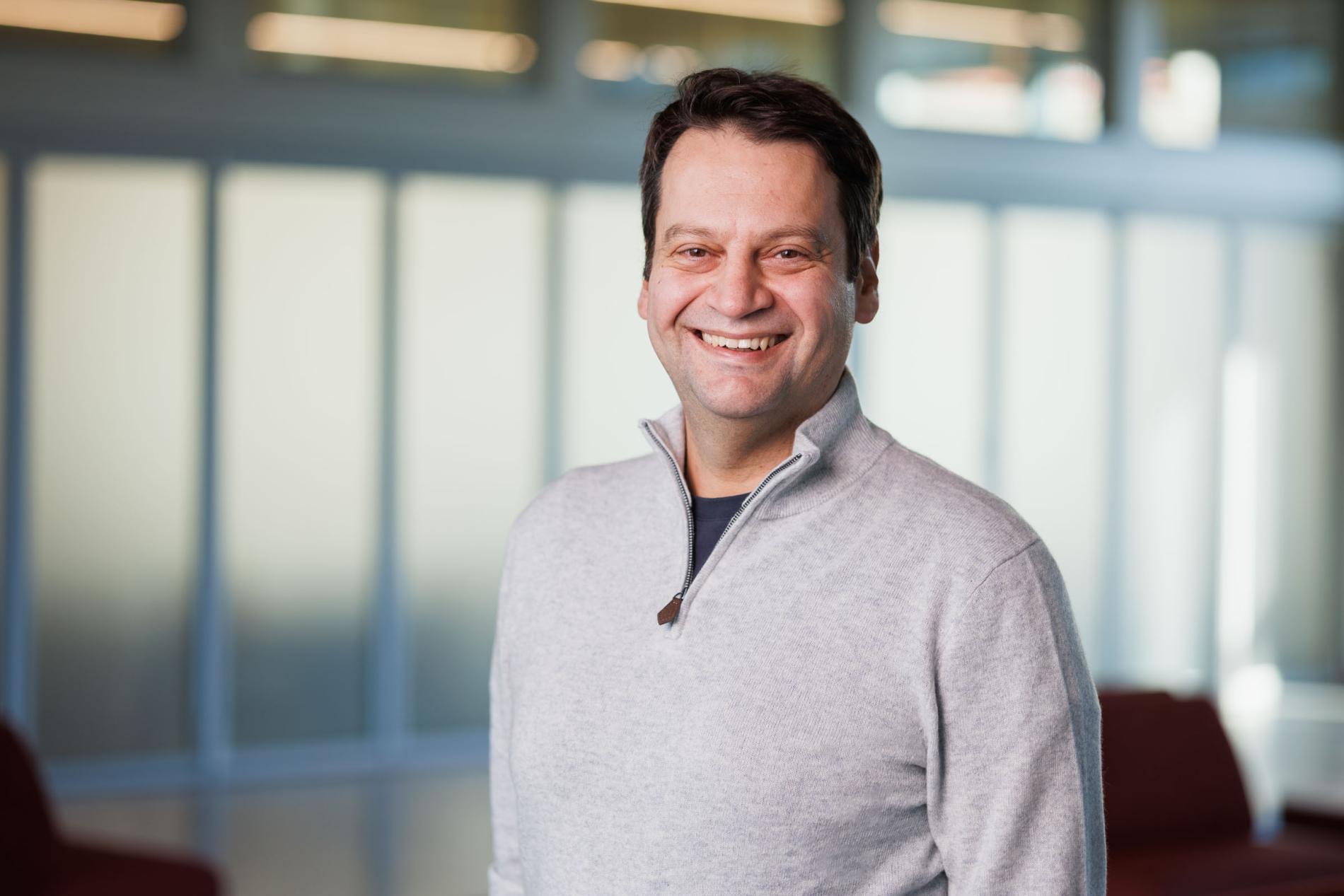 a man with short brown hair wearing a gray sweater